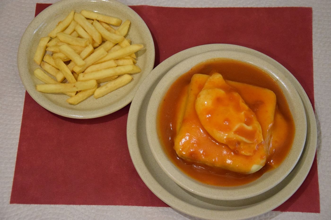 Francesinha com uma taça de batata frita, vista de cima