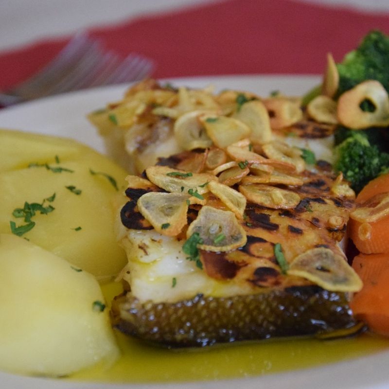 Posta de bacalhau assada com lascas de alho tostado, batata cozida, brócolos e cenoura