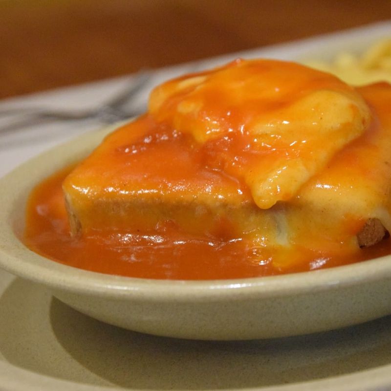 Francesinha com molho de tomate e queijo derretido