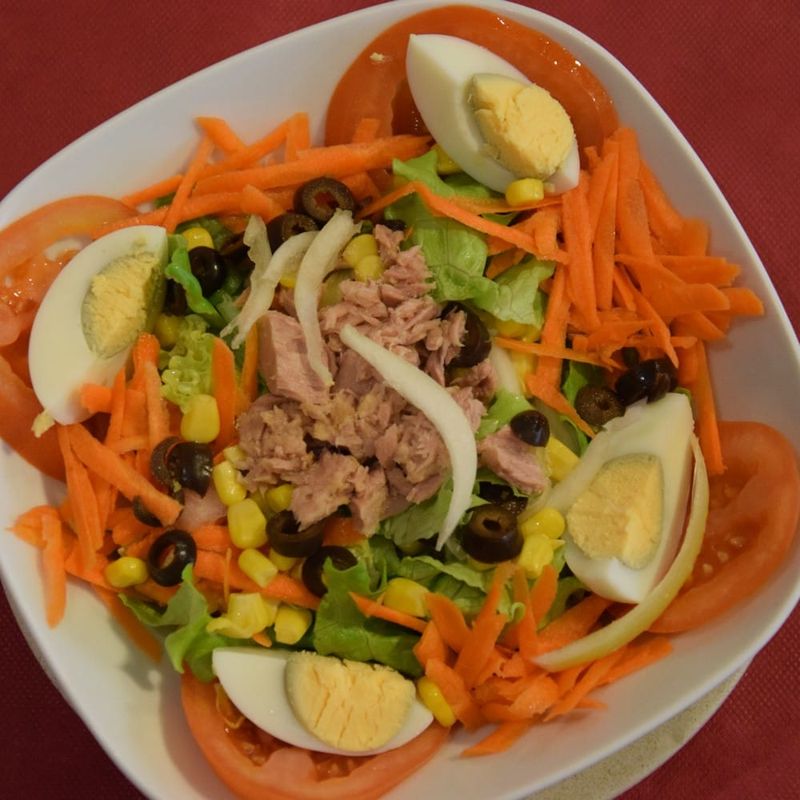 Salada Kudissama com alface, tomate, atum, ovo cozido, milho, cenoura e azeitonas