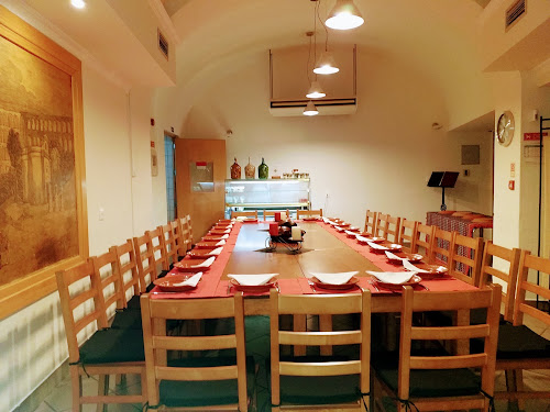 A mesa comprida posta para um grupo, sob a abóbada branca da sala do fundo